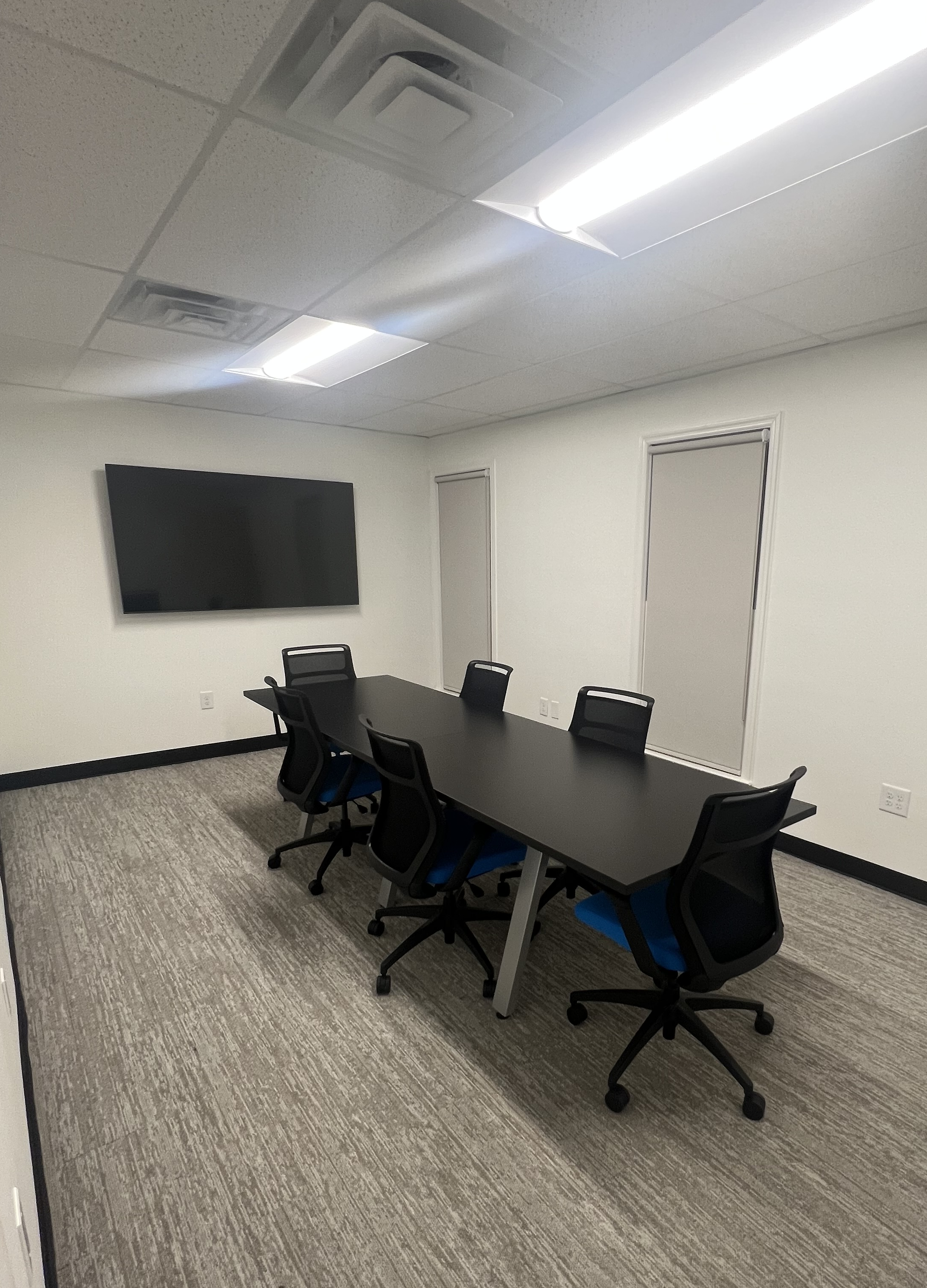 Our conference room with a long table with six office chairs and a TV on the wall.