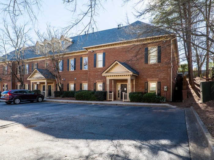 Large brick building next to trees, with car parked in front--our office building in Atlanta.